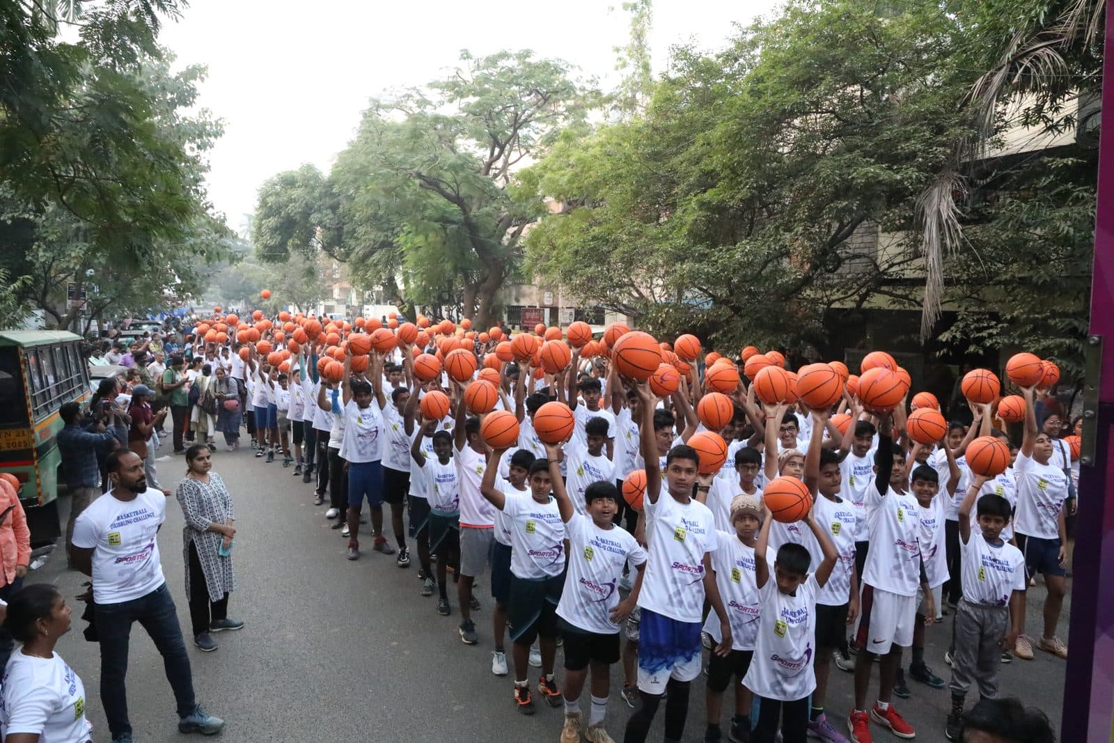 Hundreds of children dribbling basketballs along the road during the Basketball Dribbling Challenge
